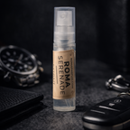Small spray bottle labeled 'Roma Serenade' on a dark surface with a watch and keys in the background.